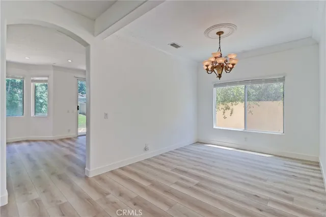 an empty room that has a dining table and a chandelier
