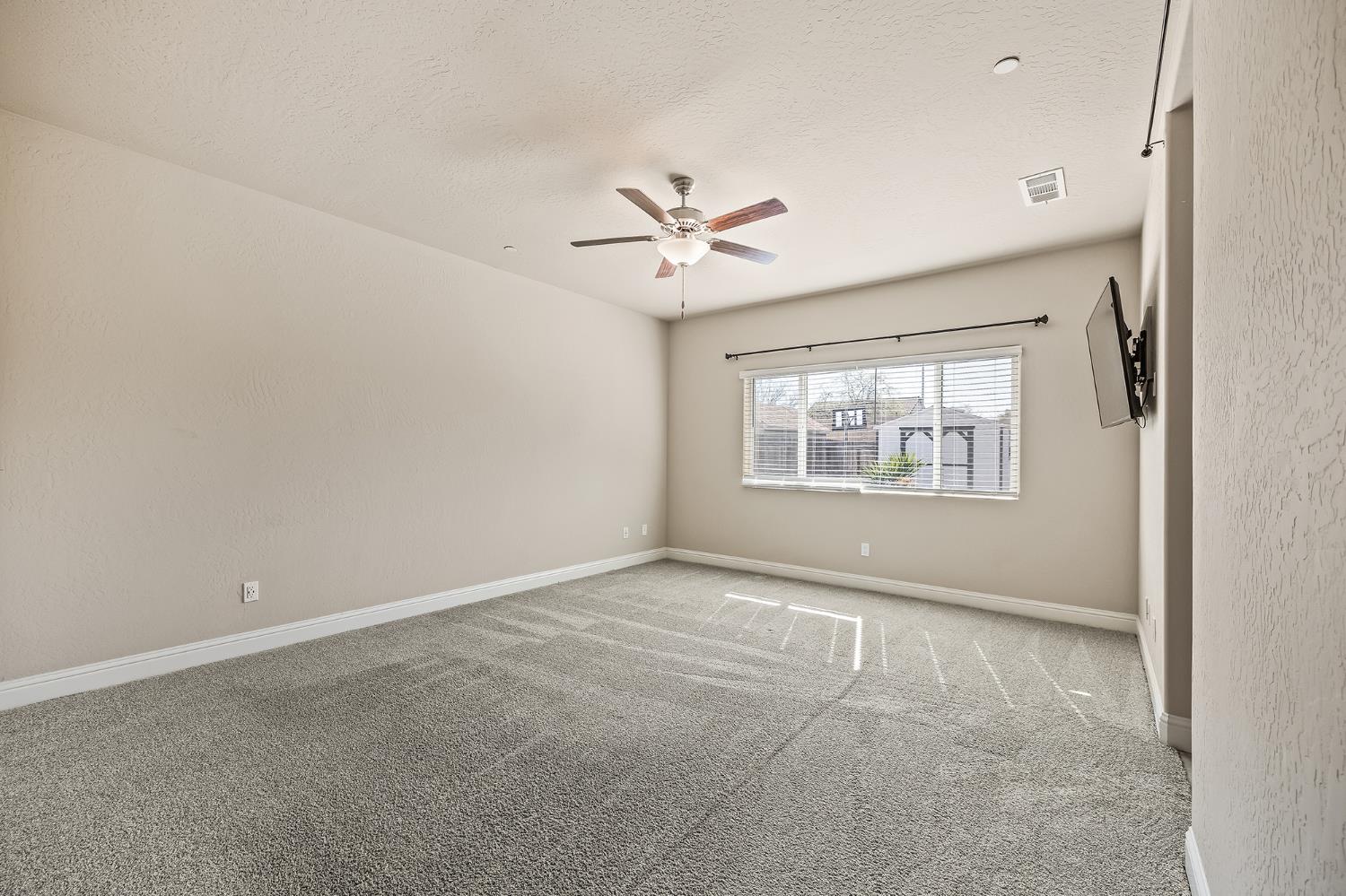 701 Strada Street Lemoore, CA 93245 - Photo 12 of 25 an empty room with chandelier fan and windows