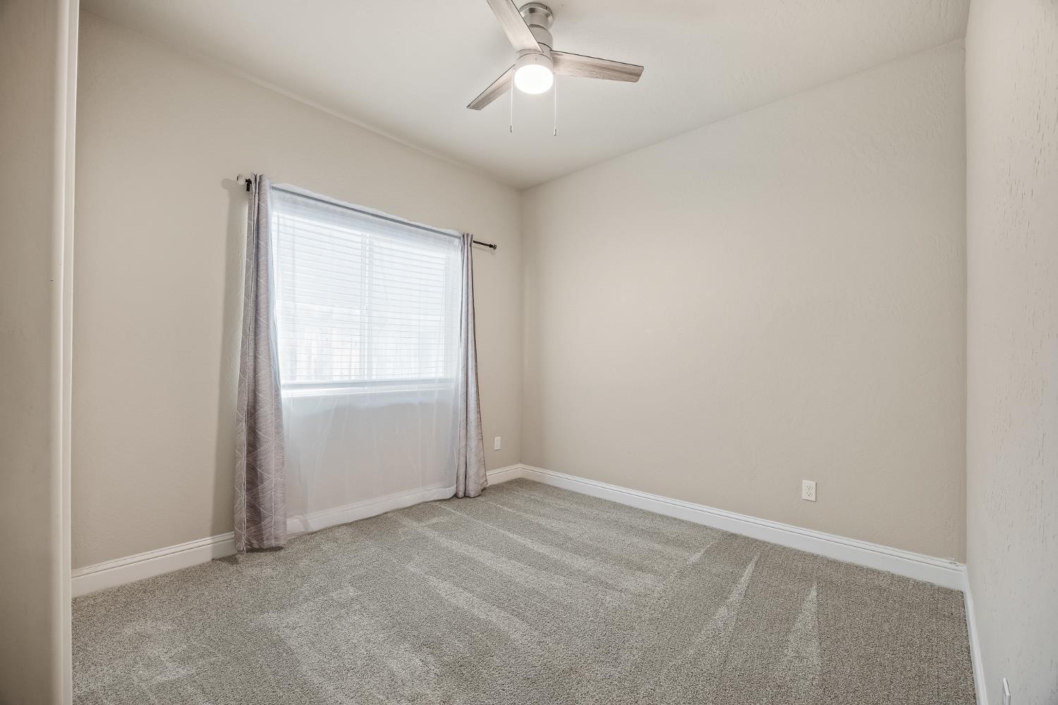 701 Strada Street Lemoore, CA 93245 - Photo 17 of 25 an empty room with a window and a ceiling fan