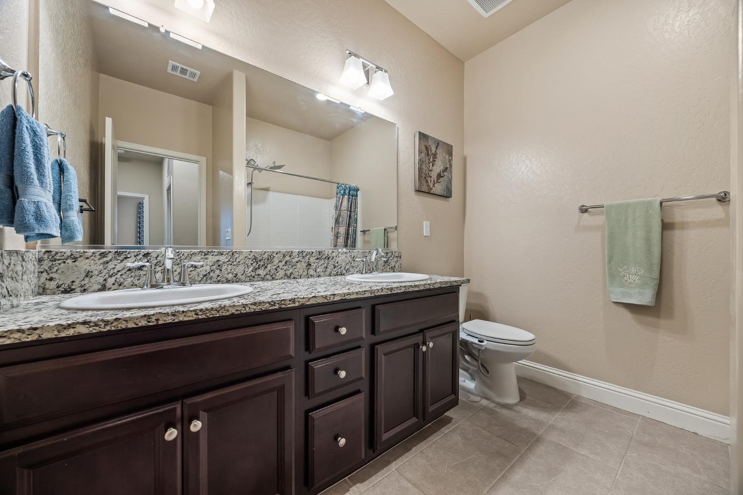 701 Strada Street Lemoore, CA 93245 - Photo 19 of 25 a bathroom with a granite countertop toilet sink and mirror