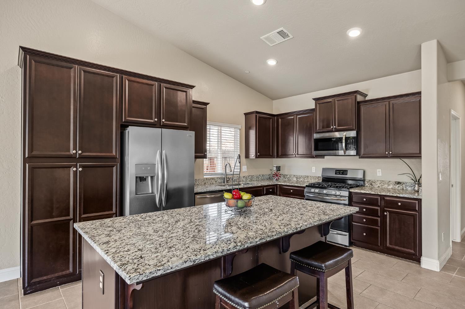 701 Strada Street Lemoore, CA 93245 - Photo 7 of 25 a kitchen with stainless steel appliances granite countertop a refrigerator and a stove top oven