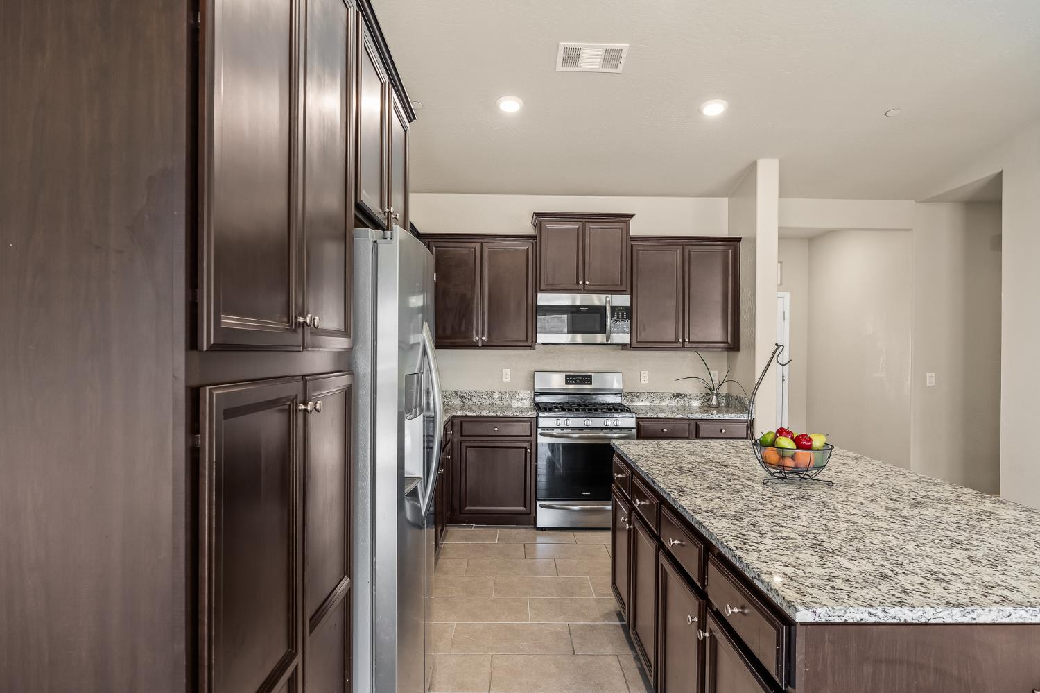 701 Strada Street Lemoore, CA 93245 - Photo 8 of 25 a kitchen with stainless steel appliances granite countertop a stove top oven a sink and dishwasher