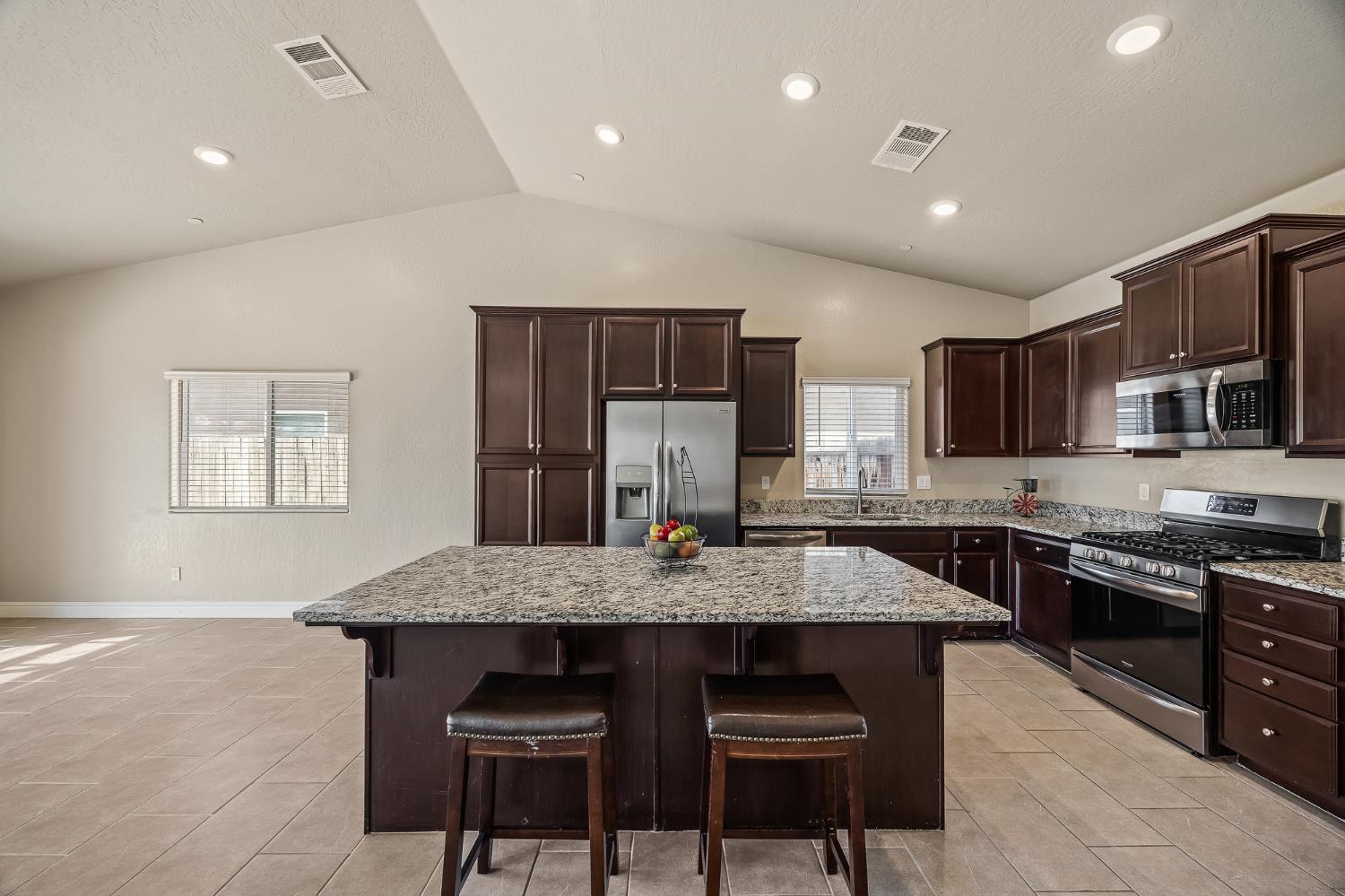 701 Strada Street Lemoore, CA 93245 - Photo 9 of 25 a kitchen with stainless steel appliances granite countertop a stove top oven a sink dishwasher a dining table and chairs