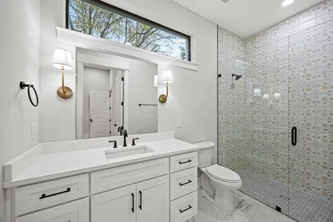 a bathroom with a toilet a sink a mirror a window and vanity