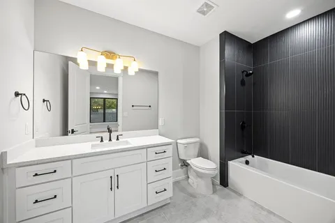 a bathroom with a double vanity sink toilet mirror and bathtub