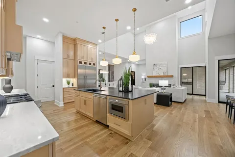 a large kitchen with stainless steel appliances kitchen island granite countertop a stove a sink a refrigerator and a dining table with wooden floor