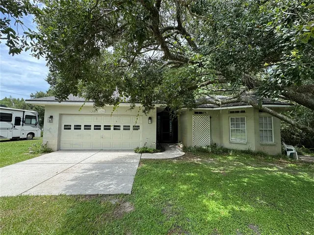 a view of a house with a yard and a large tree