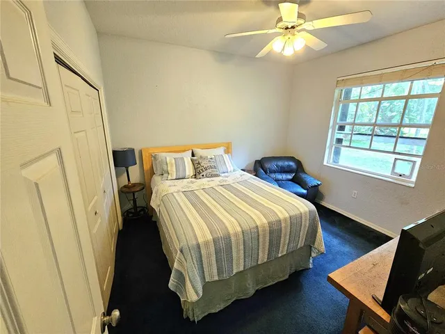 a bedroom with a bed couch and a ceiling fan