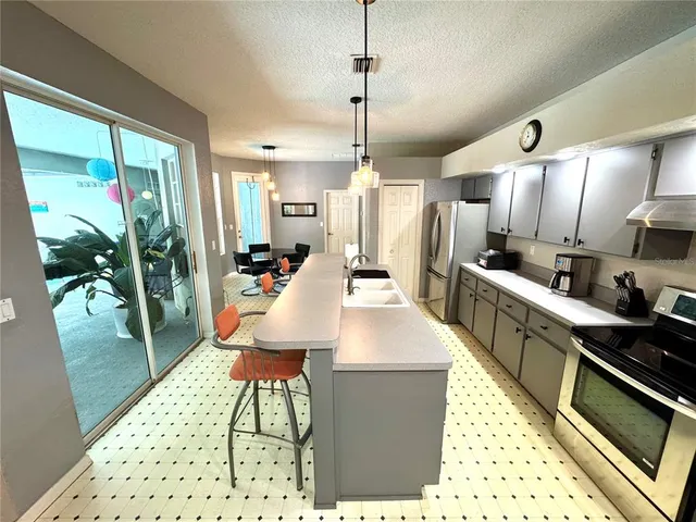 a large kitchen with sink a refrigerator and chairs