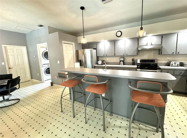 a kitchen with stainless steel appliances kitchen island granite countertop a sink a stove a dining table and chairs