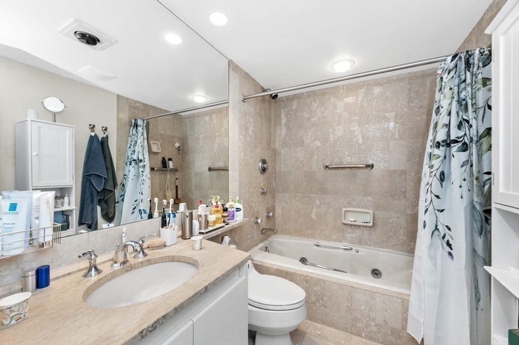 20 Rowes Wharf, Unit PH4 Boston, MA 02110 - Photo 15 of 24 a bathroom with a granite countertop sink a toilet a mirror a bathtub and shower