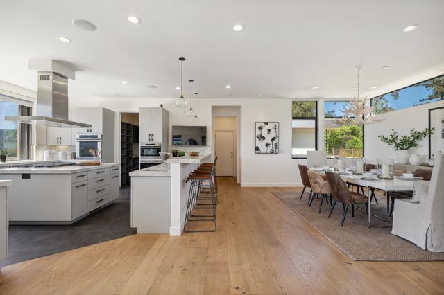 a large white kitchen with lots of counter top space and stainless steel appliances