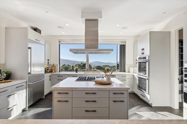 a kitchen with a stove a refrigerator and a view of living room