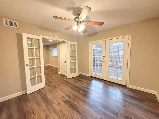 a view of an empty room with window and wooden floor