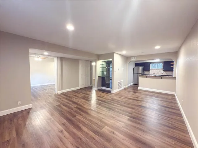 a view of a kitchen and an empty room with wooden floor