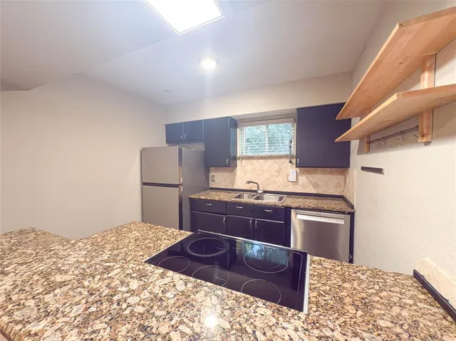 a kitchen with stainless steel appliances kitchen island granite countertop a refrigerator and a stove top oven
