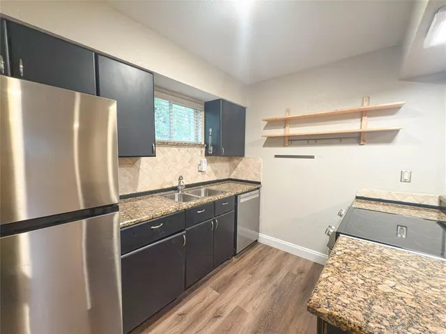 a kitchen with granite countertop a refrigerator and a sink