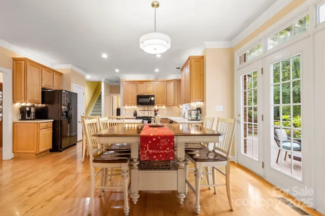 a kitchen with stainless steel appliances kitchen island granite countertop a refrigerator a stove top oven a sink dishwasher and a dining table with wooden floor
