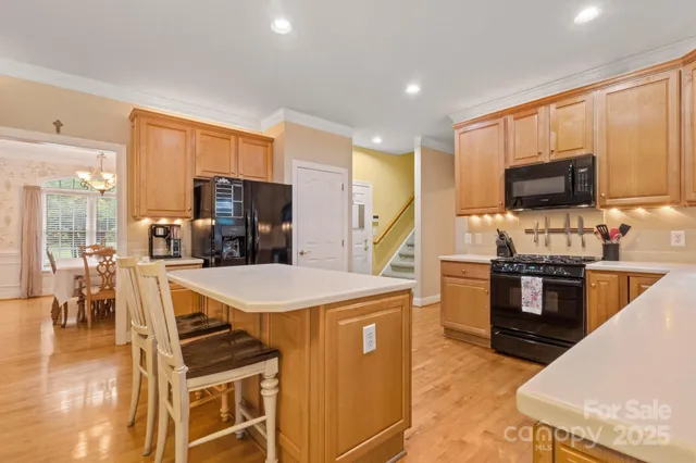 a kitchen with kitchen island a stove a sink a oven with a dining table and chairs