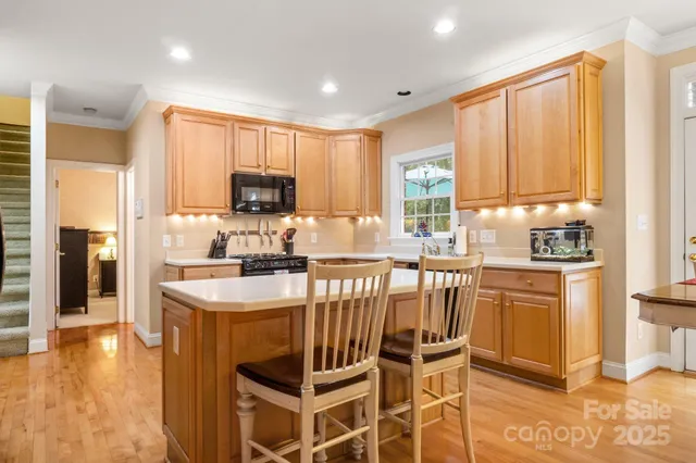 a kitchen with stainless steel appliances granite countertop a stove top oven a refrigerator a sink and a dining table with wooden floor