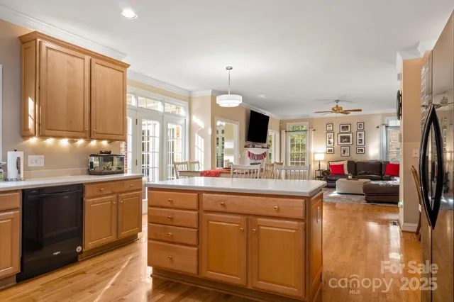 a kitchen with kitchen island granite countertop a sink dishwasher stove and white cabinets with wooden floor