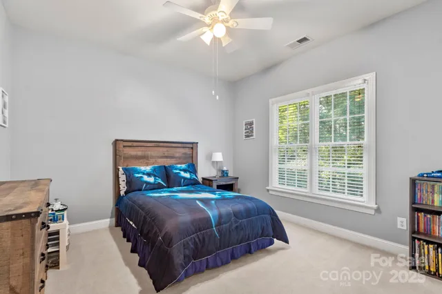 a bedroom with a bed a bookshelf and a large window