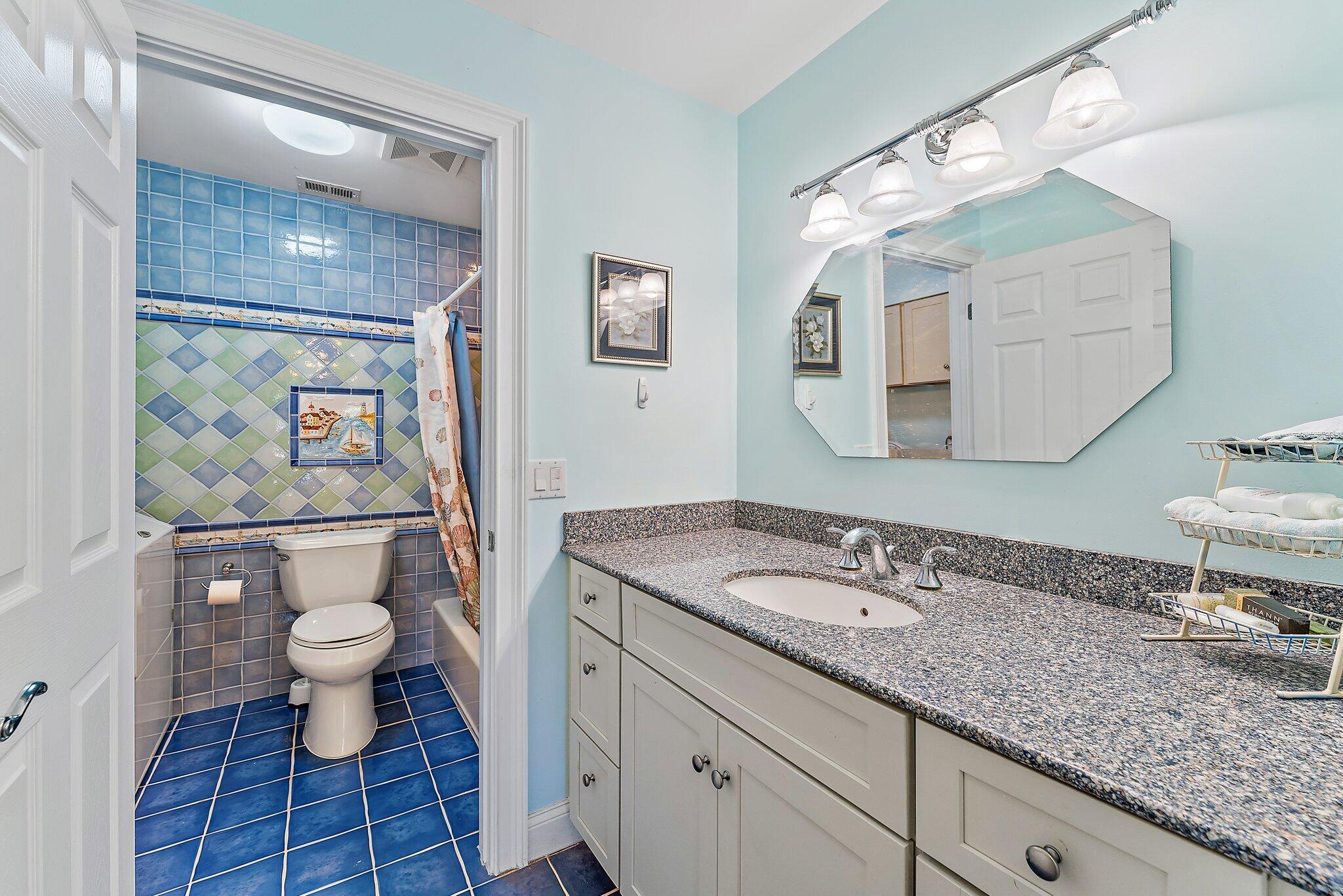 717 Highway 1, Unit 812 Jupiter, FL 33477 - Photo 19 of 41 a bathroom with a granite countertop sink a toilet and a mirror