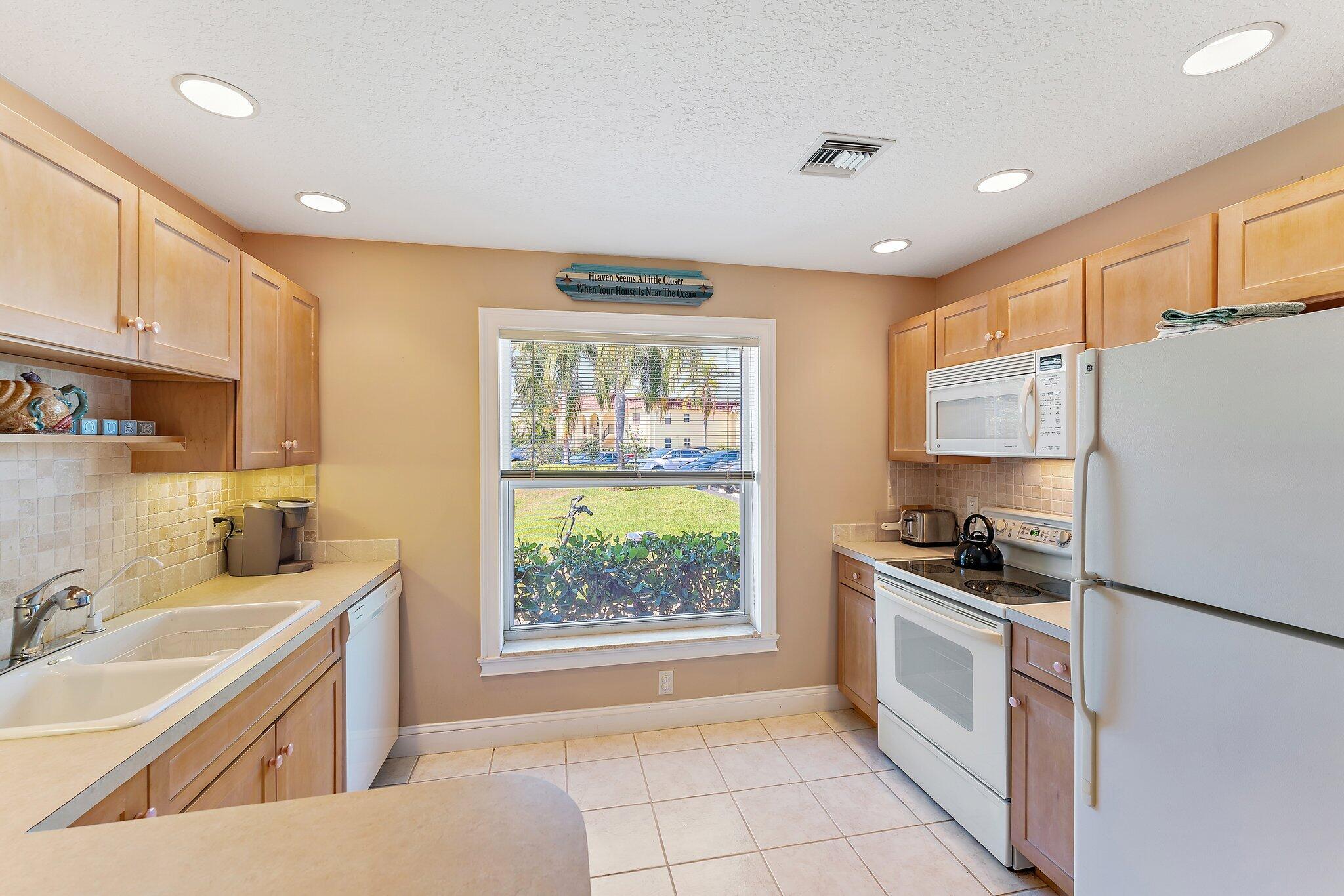 717 Highway 1, Unit 812 Jupiter, FL 33477 - Photo 7 of 41 a kitchen with a sink a stove a refrigerator cabinets and a window