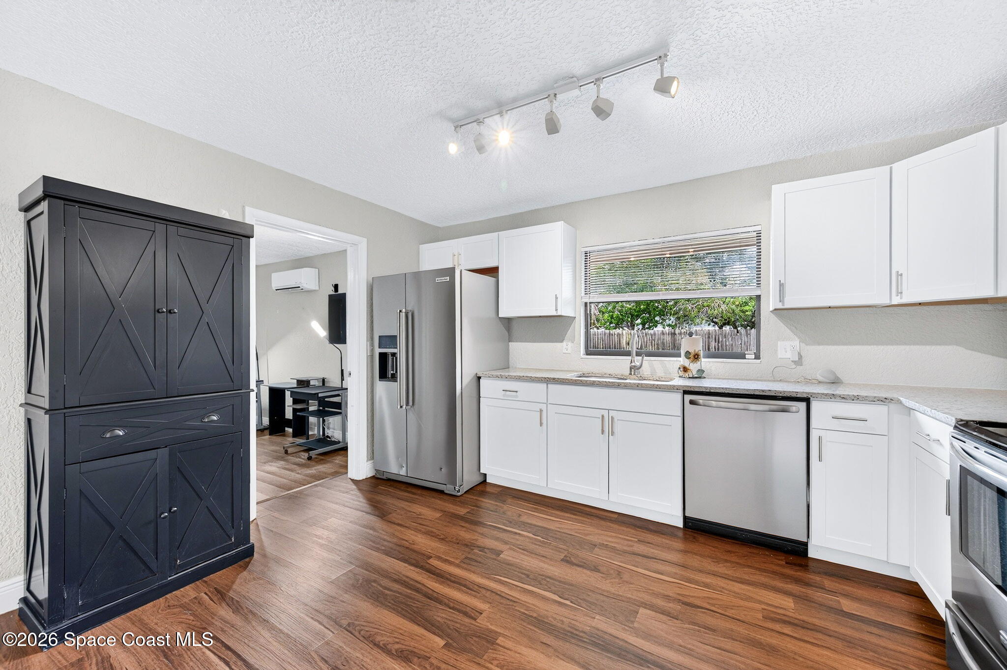 996 Botany Lane Rockledge, FL 32955 - Photo 13 of 35 a kitchen with stainless steel appliances granite countertop a refrigerator a sink and white cabinets with wooden floor