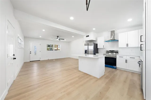 a large kitchen with stainless steel appliances granite countertop a stove a sink dishwasher and a refrigerator with wooden floor