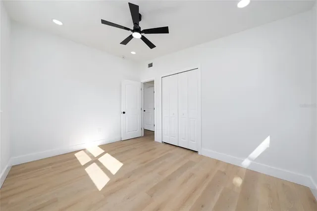 a view of empty room with wooden floor and fan