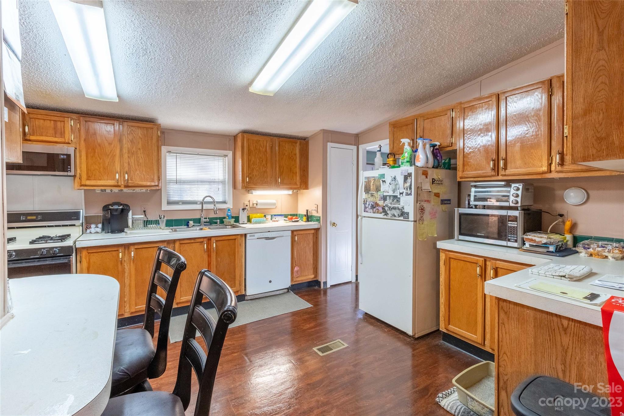 170 Painter Street Sylva, NC 28779 - Photo 9 of 48 a kitchen with stainless steel appliances granite countertop a refrigerator a sink dishwasher a stove top oven a dining table and chairs with wooden floor