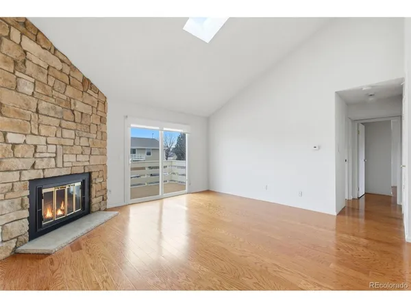 a view of an empty room with wooden floor fireplace and a window