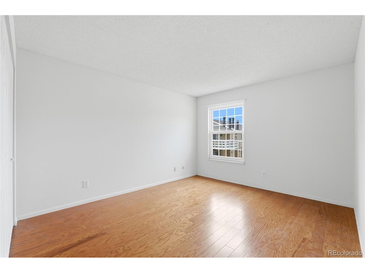 10251 West 44th Avenue, Unit 208 Wheat Ridge, CO 80033 - Photo 17 of 28 a view of an empty room with wooden floor and a window