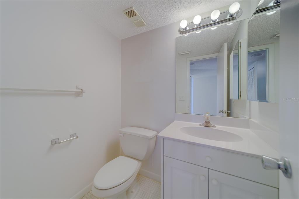 1 Windrush Boulevard, Unit 28 Indian Rocks Beach, FL 33785 - Photo 35 of 68 a bathroom with a toilet a sink a light fixture and mirror