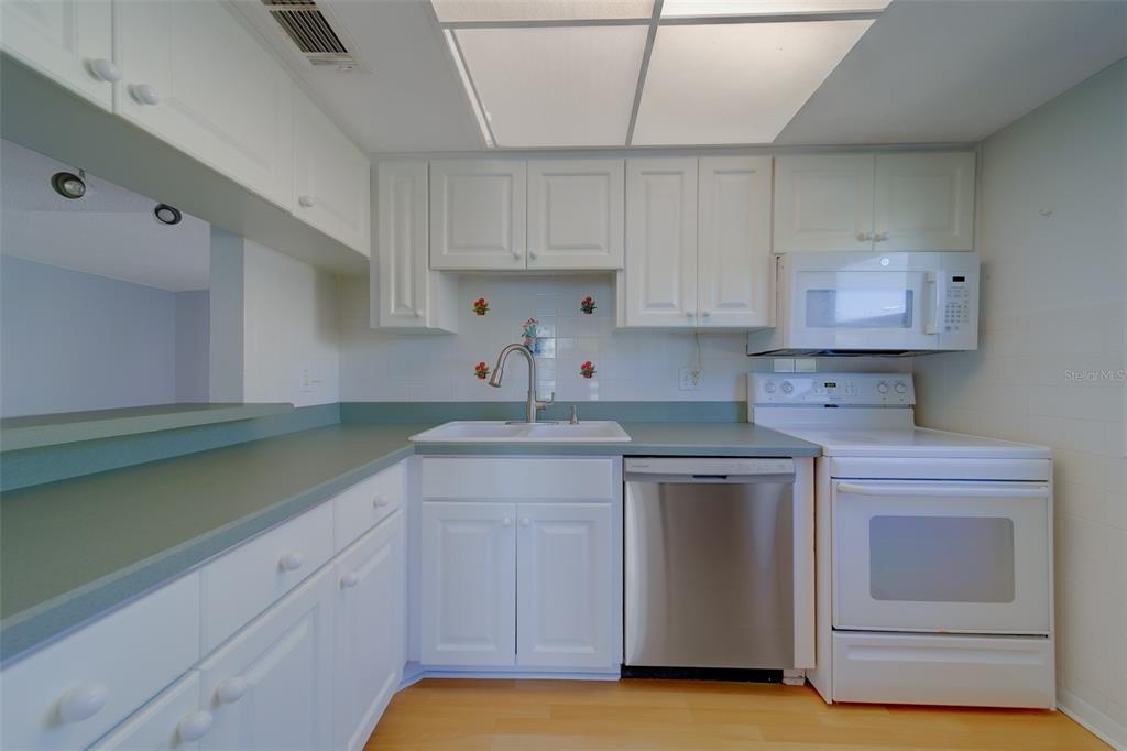 1 Windrush Boulevard, Unit 28 Indian Rocks Beach, FL 33785 - Photo 4 of 68 a kitchen with stainless steel appliances granite countertop a sink and cabinets