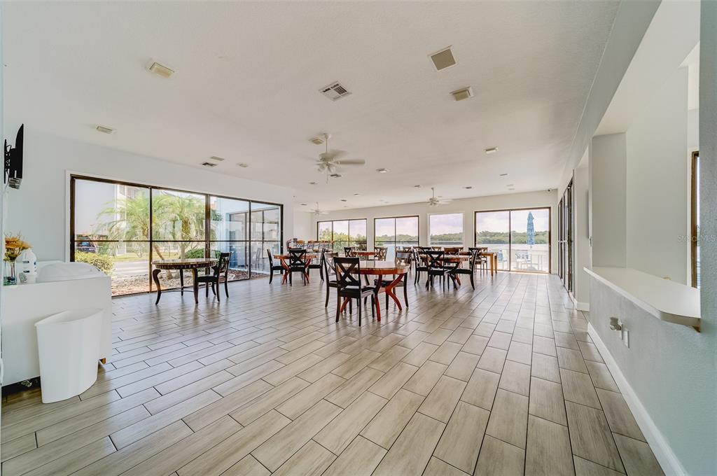 1 Windrush Boulevard, Unit 28 Indian Rocks Beach, FL 33785 - Photo 50 of 68 a dining room with furniture floor to ceiling windows and wooden floor