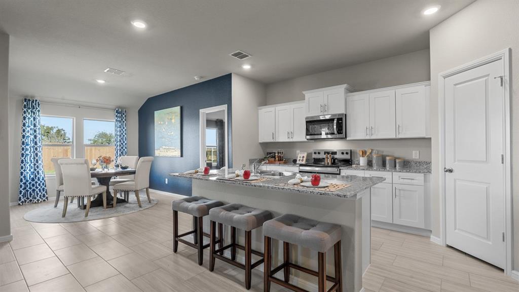 a kitchen with stainless steel appliances granite countertop a stove top oven a sink a dining table and chairs with wooden floor