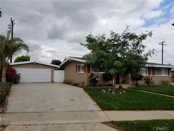 a front view of a house with a garden and trees