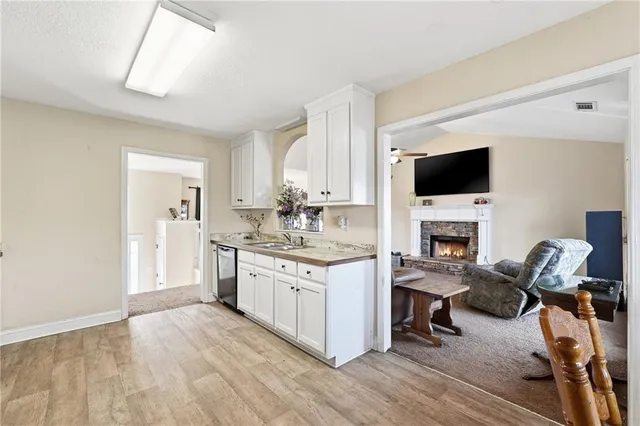 a view of a kitchen with granite countertop a stove top oven a sink dishwasher and a fireplace with wooden floor