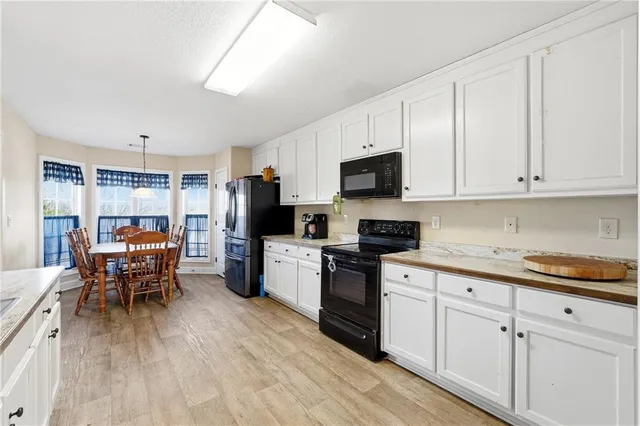 a kitchen with stainless steel appliances granite countertop a stove top oven a sink dishwasher a dining table and chairs with wooden floor