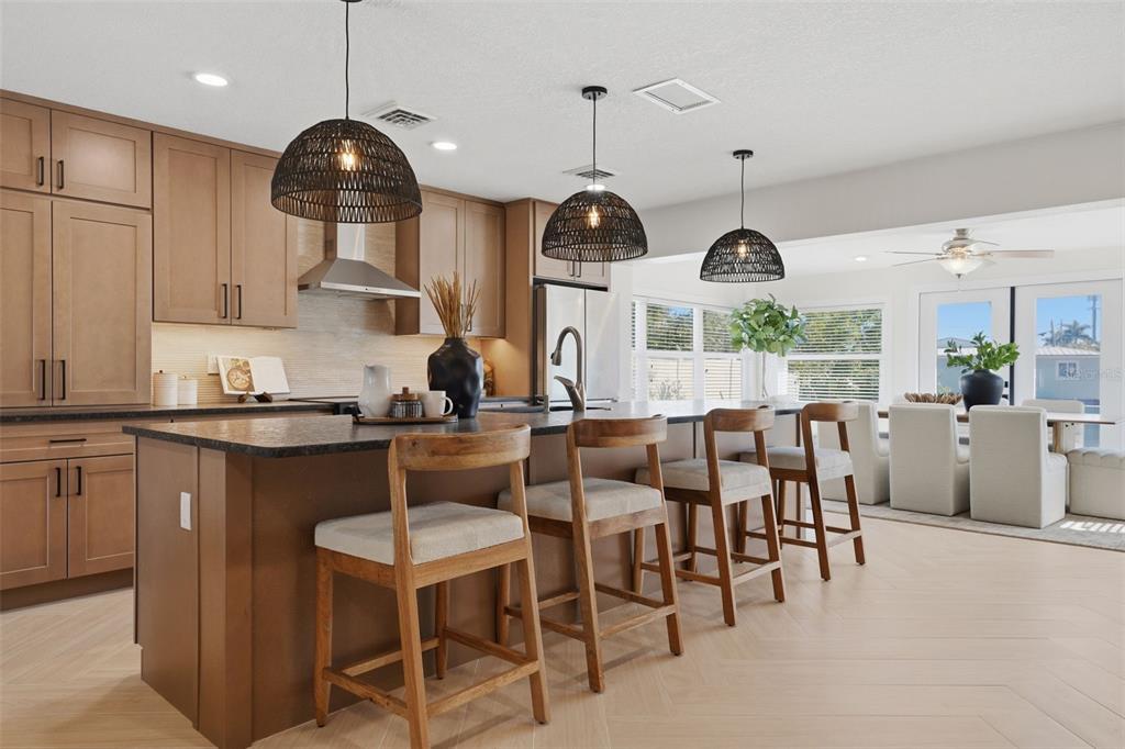 501 65th Street Holmes Beach, FL 34217 - Photo 15 of 61 a kitchen with stainless steel appliances granite countertop a stove a sink a dining table and chairs with wooden floor