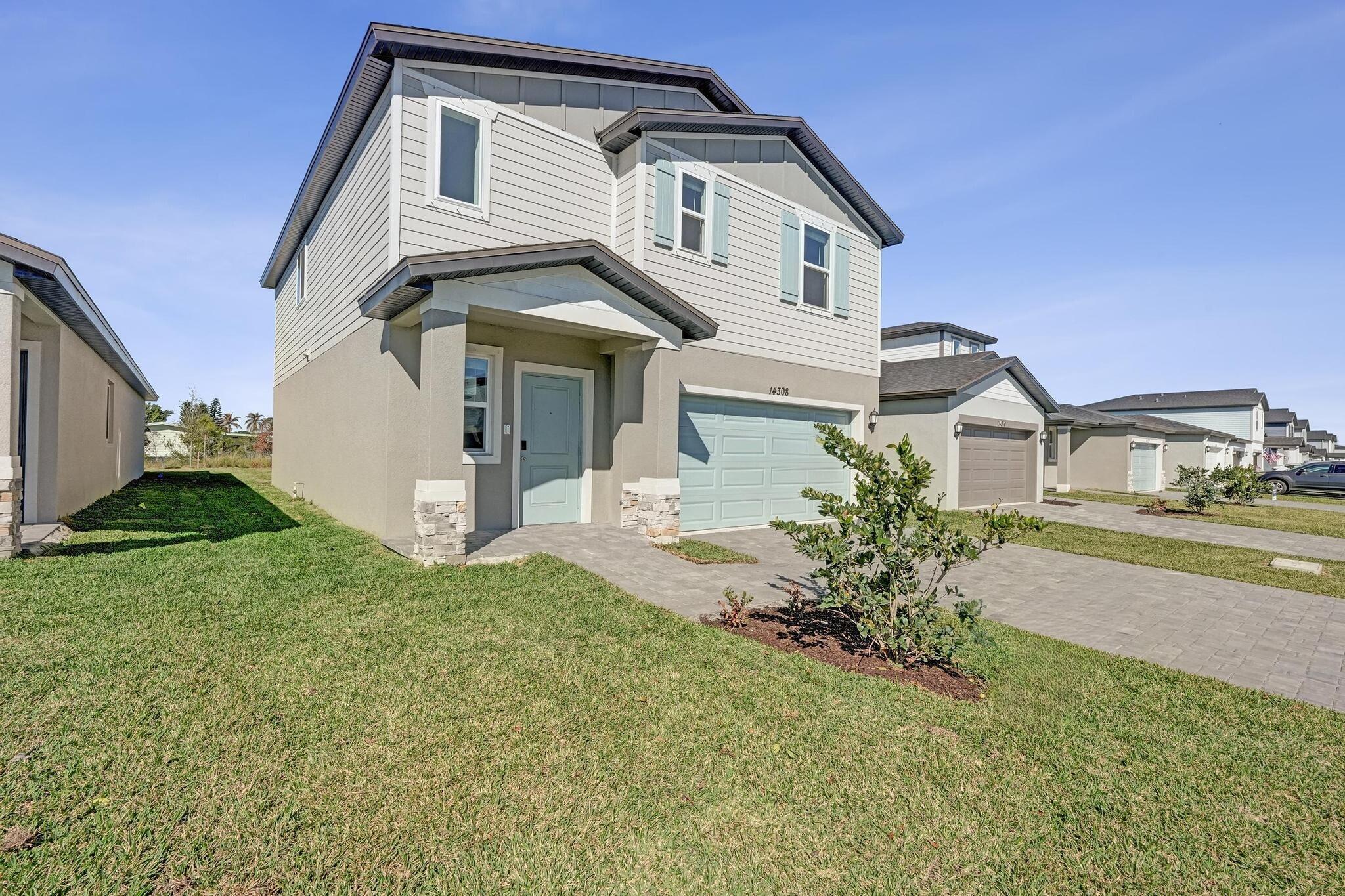 14308 Southwest New Dawn Road Indiantown, FL 34956 - Photo 2 of 25 a front view of a house with a yard and garage