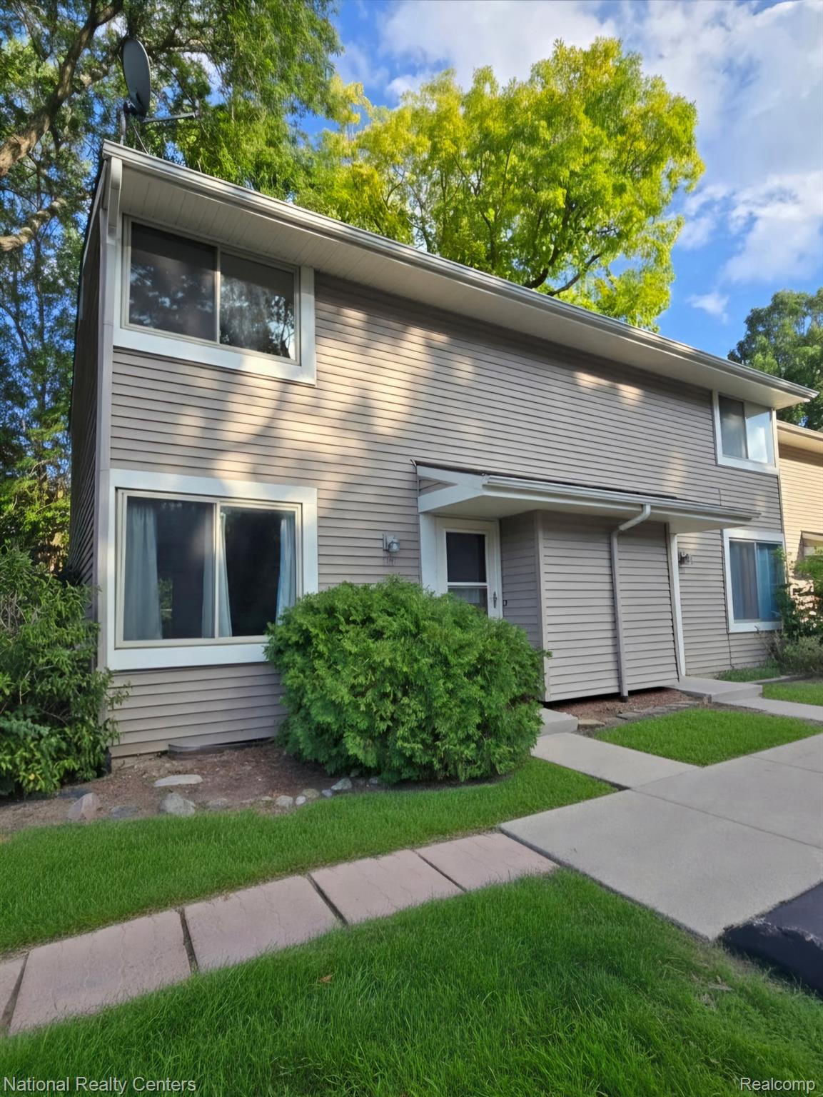 616 Rickett Road, Unit 130 Brighton, MI 48116 - Photo 2 of 20 Two-story exterior with horizontal siding, white trim windows, and a paved walkway