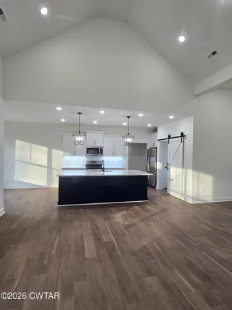 a large white kitchen with kitchen island granite countertop a sink a counter space and stainless steel appliances