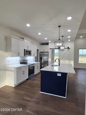 a large kitchen with stainless steel appliances kitchen island a large counter top and a wooden floors