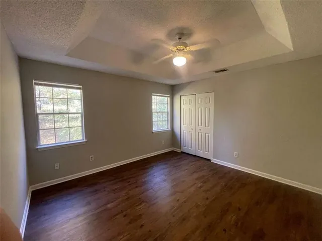 a view of an empty room with a window and wooden floor