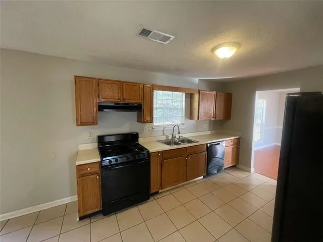 a kitchen with granite countertop a refrigerator and a stove top oven