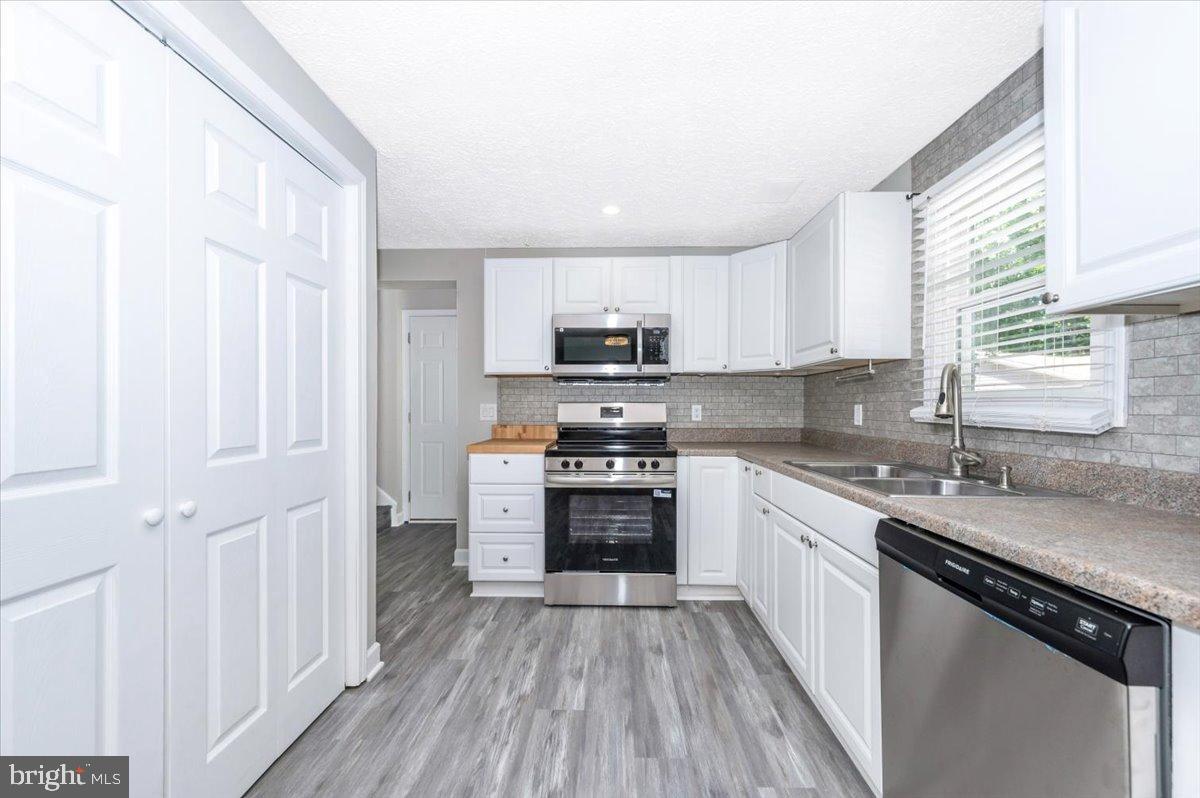 12284 Bandera Lane Lusby, MD 20657 - Photo 15 of 55 a kitchen with granite countertop a stove top oven a sink dishwasher and a refrigerator with wooden floor