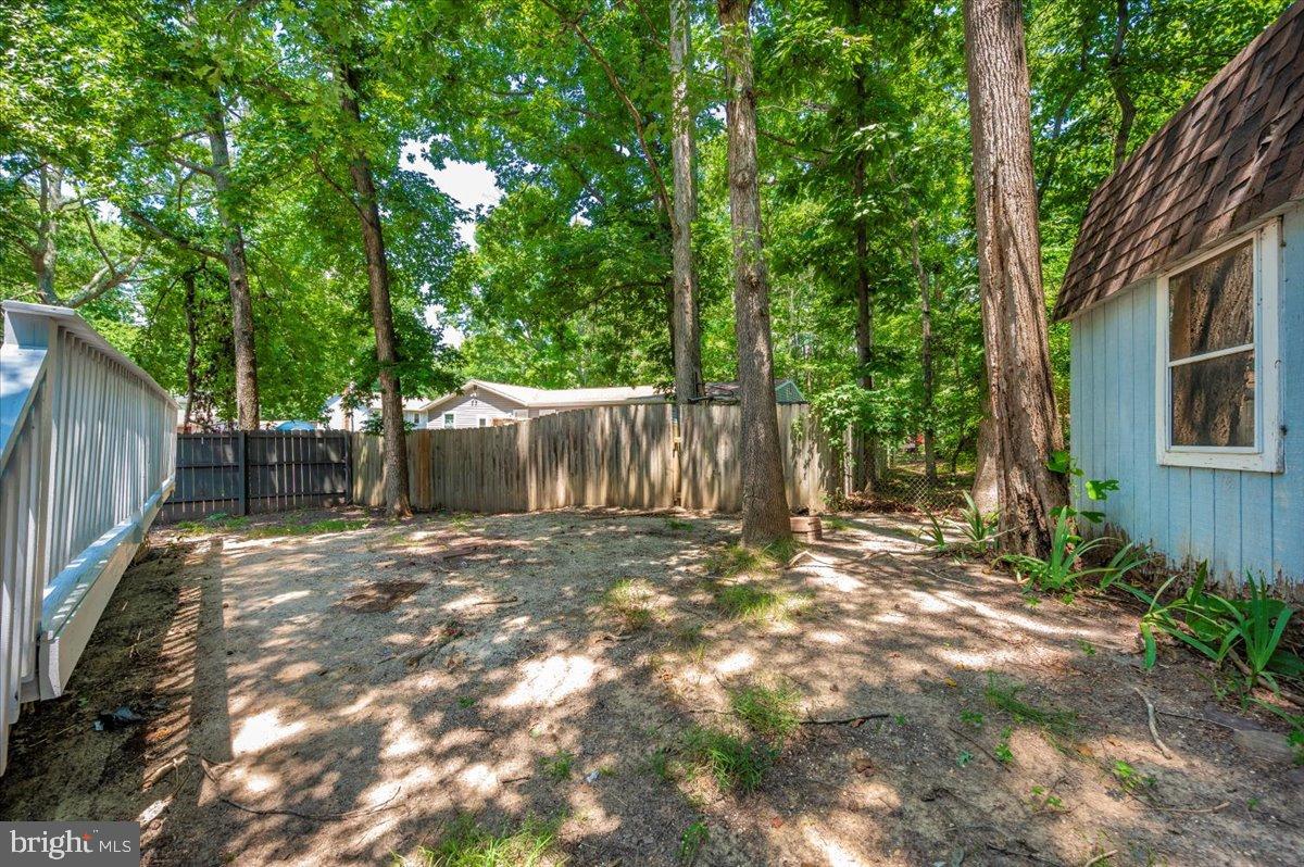 12284 Bandera Lane Lusby, MD 20657 - Photo 43 of 55 a backyard of a house with large trees and outdoor seating